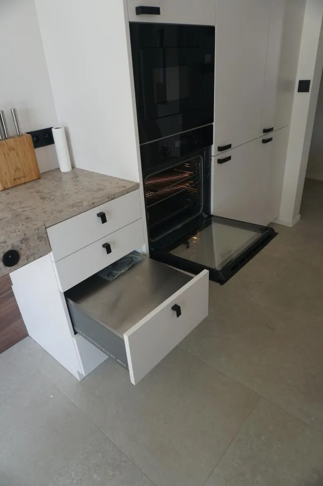 De oven met open deur en uitgeschoven hulplade om warme schotels veilig te deponeren.