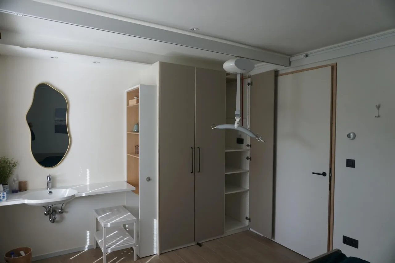 De plafondrail loopt vanuit de kleerkast tot boven de bedden.