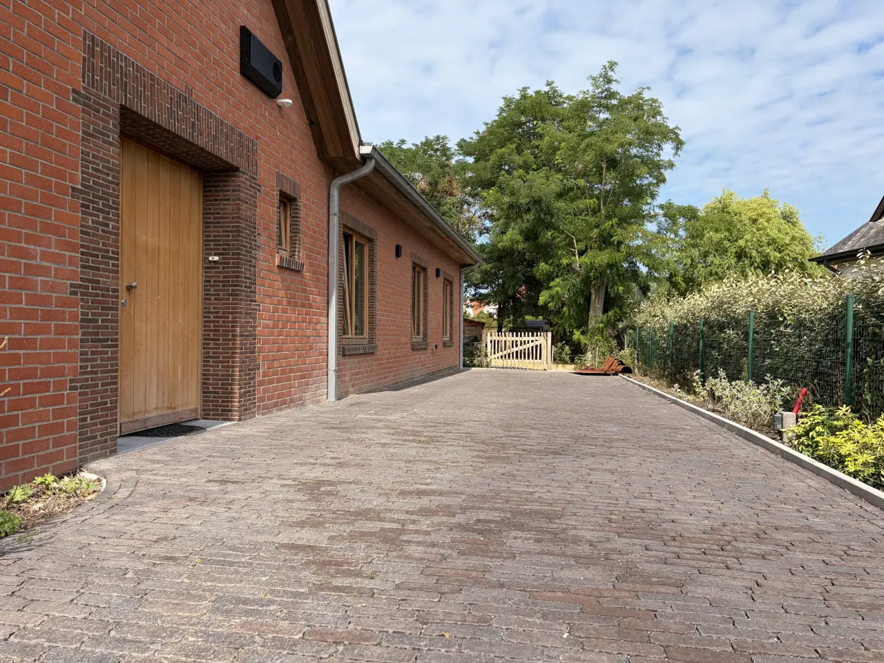 De brede oprit van 4 m op 27 m langs de zijgevel van de woning.